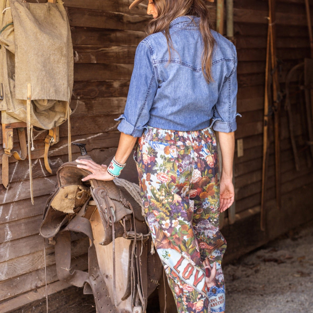 
                  
                    Model wearing linen blend artist pants with 1854 floral art, heart-in-hand symbol, and “Love one another” handwritten script – Market of Stars.
                  
                