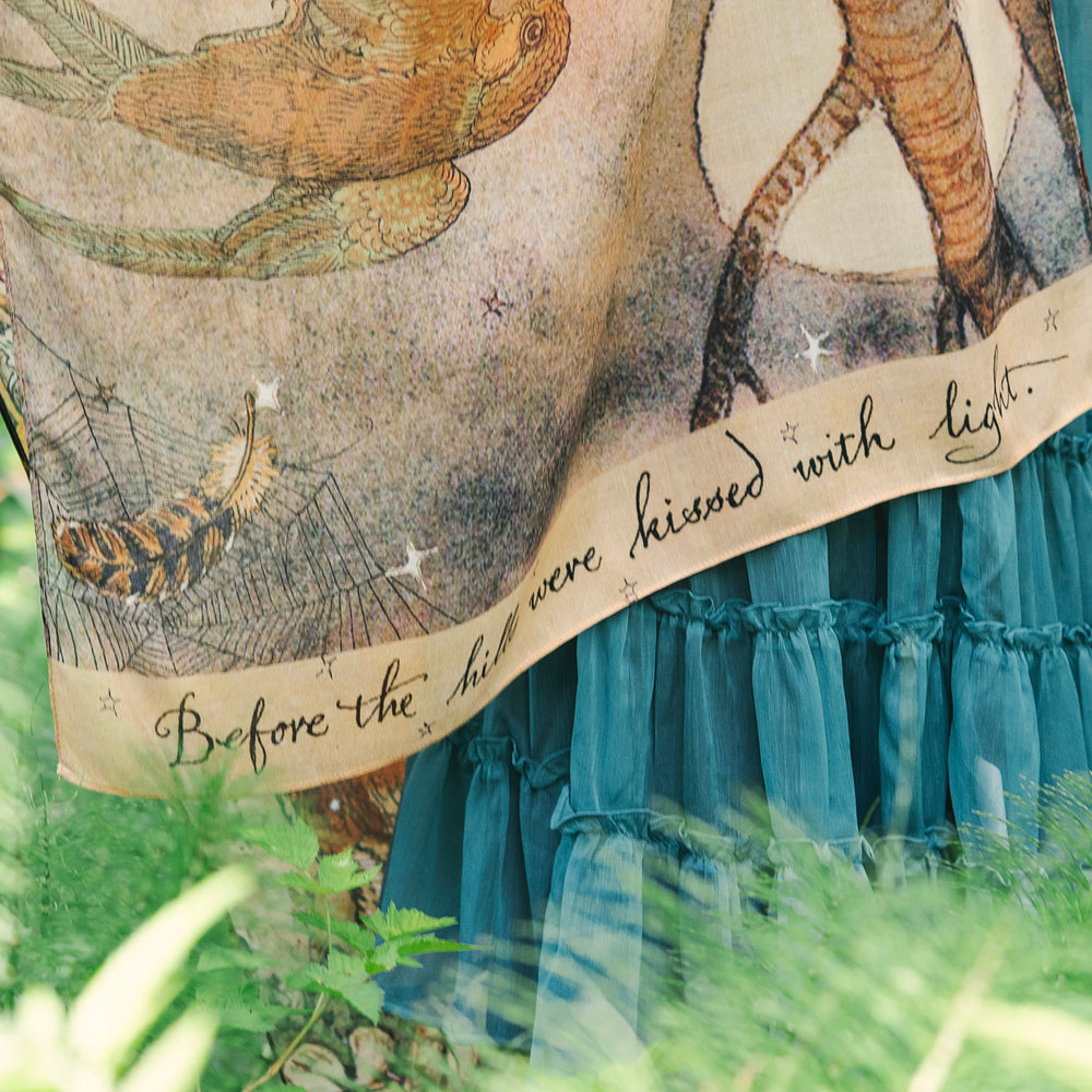 
                  
                    Model wearing an enchanting scarf featuring Charles van Sandwyck's illustrations, crafted from airy bamboo-based viscose with a touch of whimsical magic - Market of Stars
                  
                