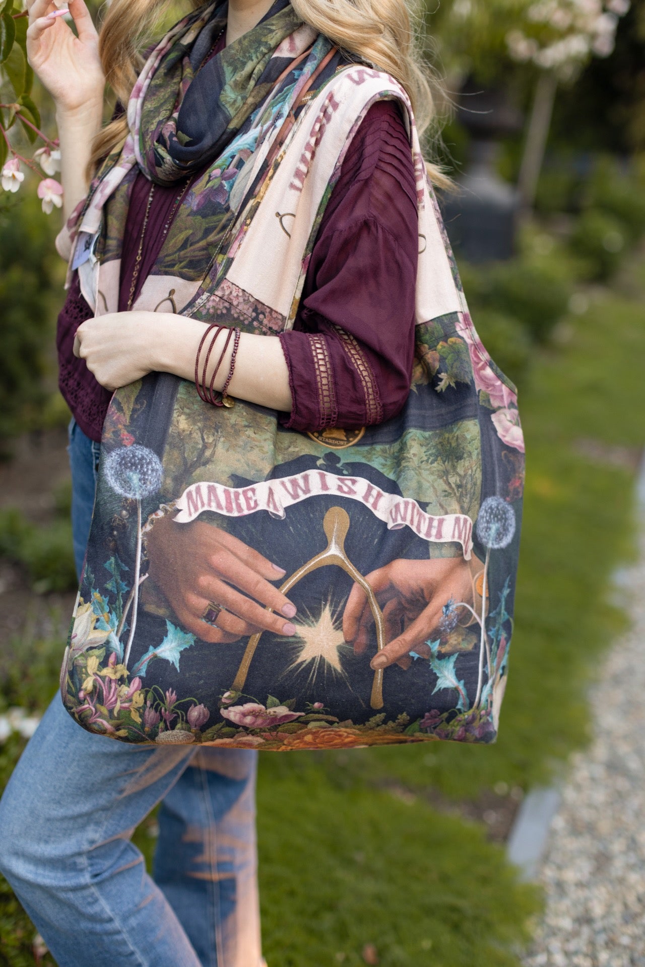Model holding linen blend market tote featuring Victorian wishbone–vintage coin–evening star–dandelion–and “Best Wishes” banner on floral background – Market of Stars