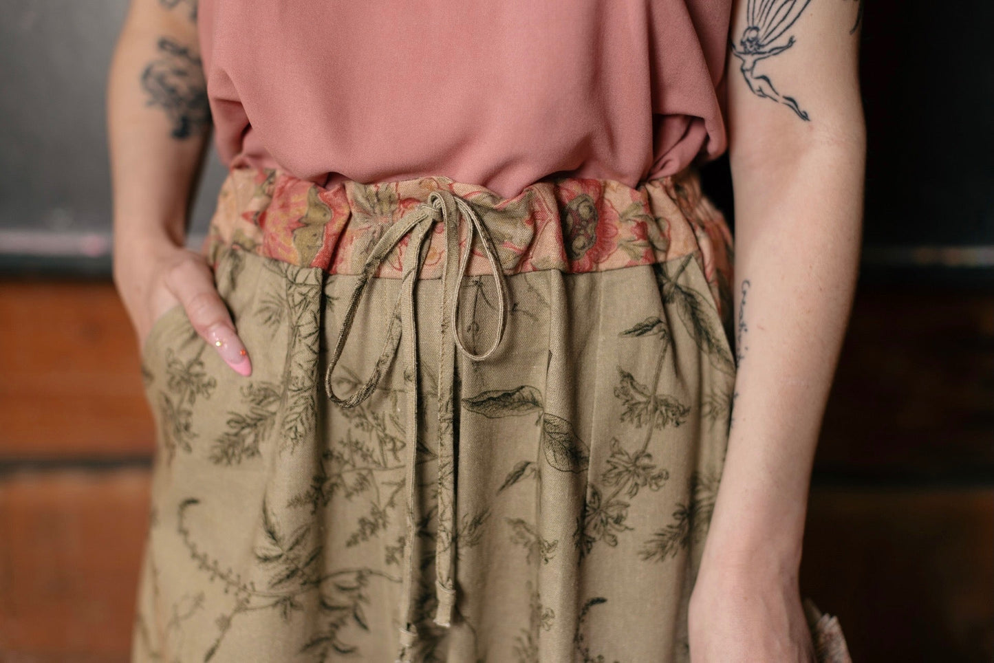 Model wearing artist pants in sage featuring reimagined vintage 1846 map of a woman’s heart with playful updated place names – Market of Stars