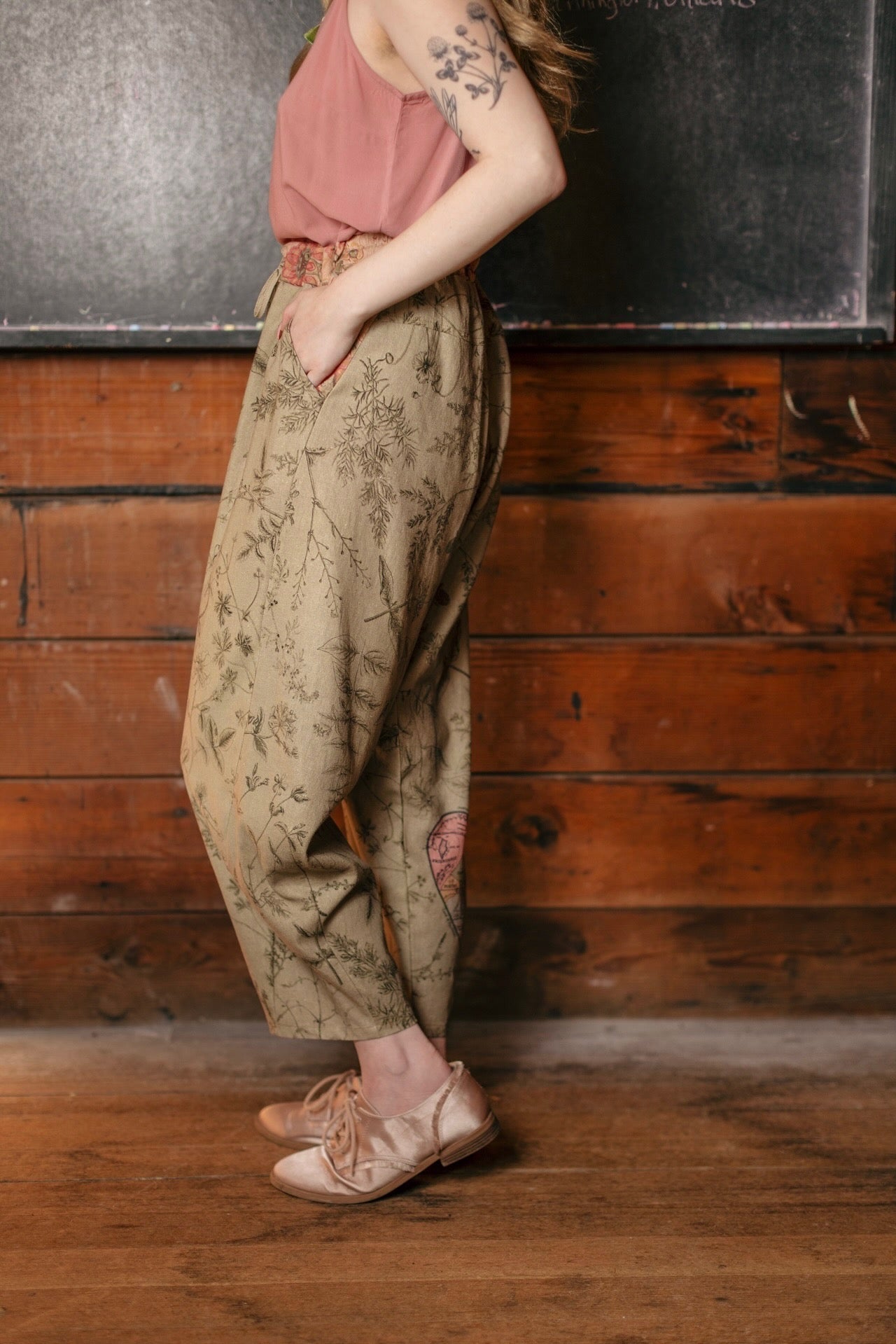 Model wearing artist pants in sage featuring reimagined vintage 1846 map of a woman’s heart with playful updated place names – Market of Stars