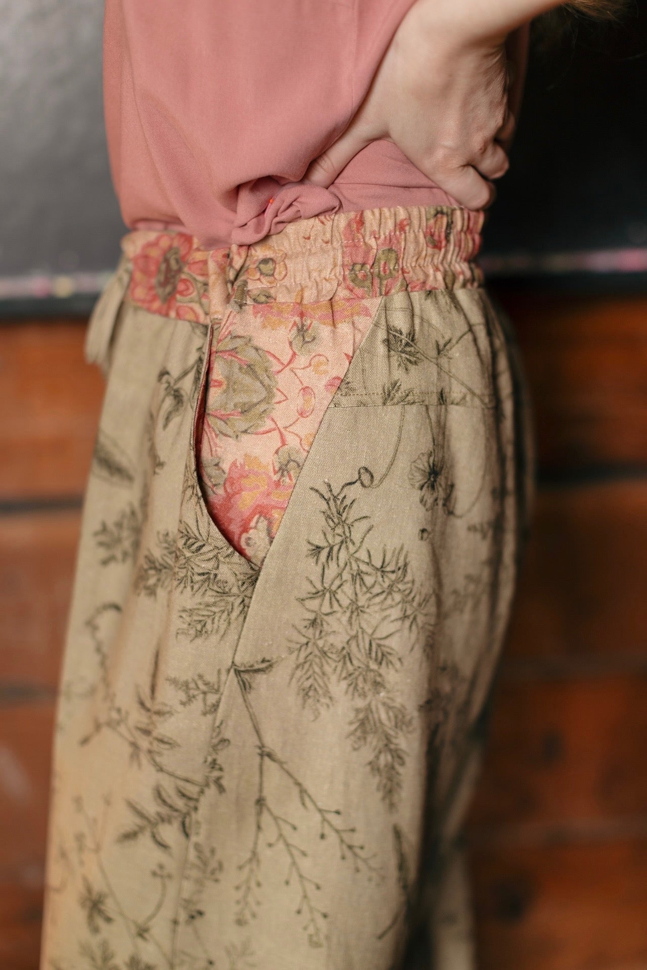 Model wearing artist pants in sage featuring reimagined vintage 1846 map of a woman’s heart with playful updated place names – Market of Stars