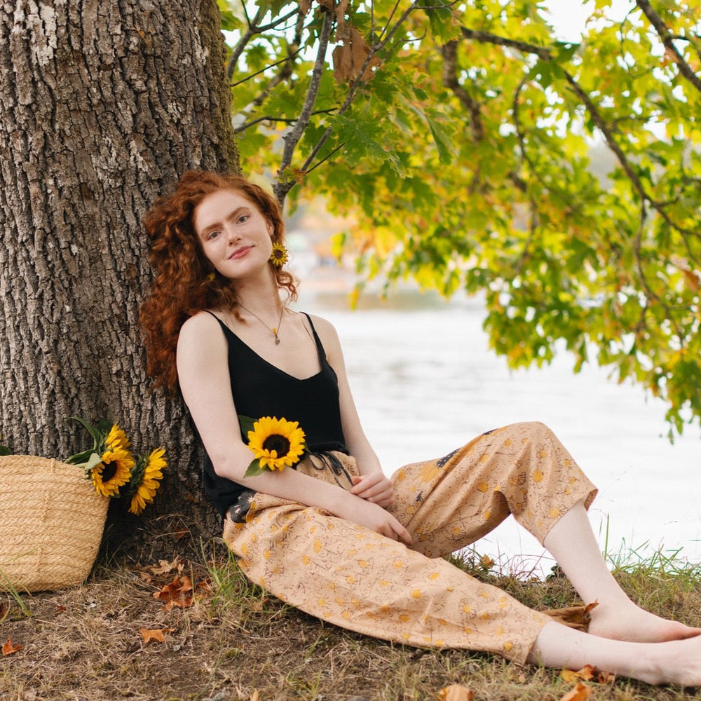 
                  
                    Model wearing the Milk & Honey Artist Pants featuring playful 1904 Brooklyn poster art and antique woodcut star and floral details in vintage-inspired tones – Market of Stars.
                  
                