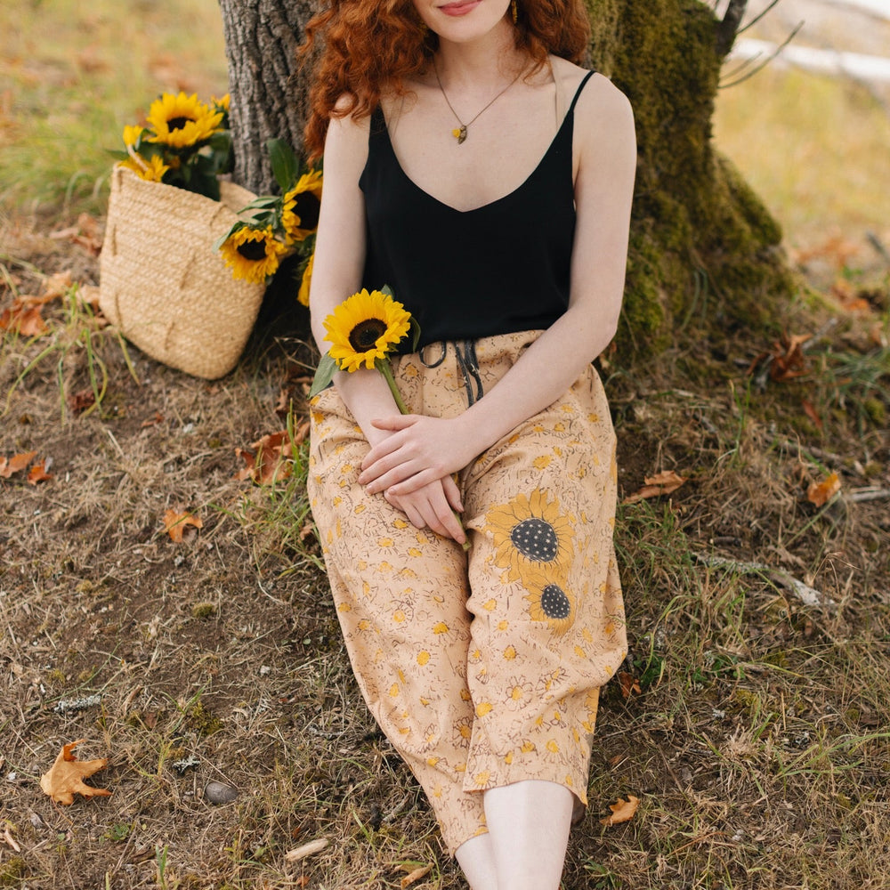 
                  
                    Model wearing the Milk & Honey Artist Pants featuring playful 1904 Brooklyn poster art and antique woodcut star and floral details in vintage-inspired tones – Market of Stars.
                  
                