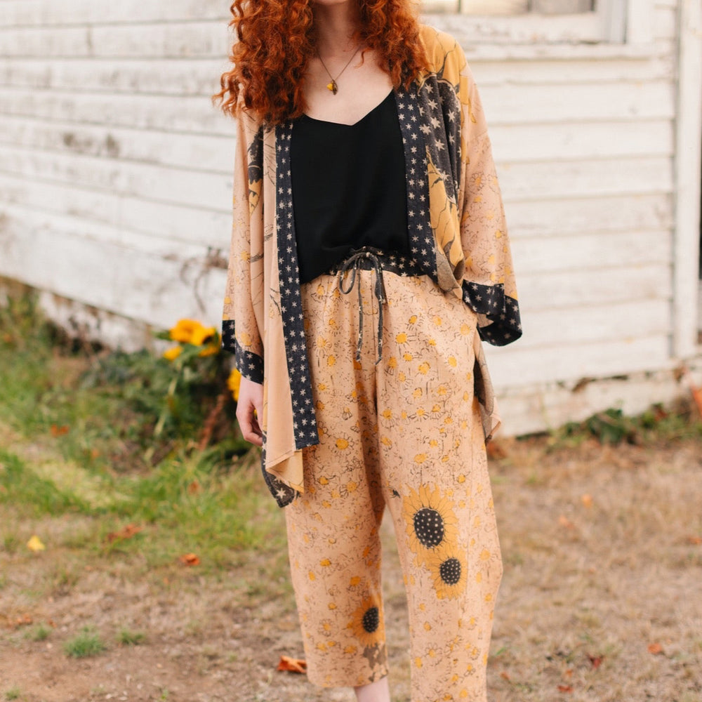 
                  
                    Model wearing the Milk & Honey Artist Pants featuring playful 1904 Brooklyn poster art and antique woodcut star and floral details in vintage-inspired tones – Market of Stars.
                  
                