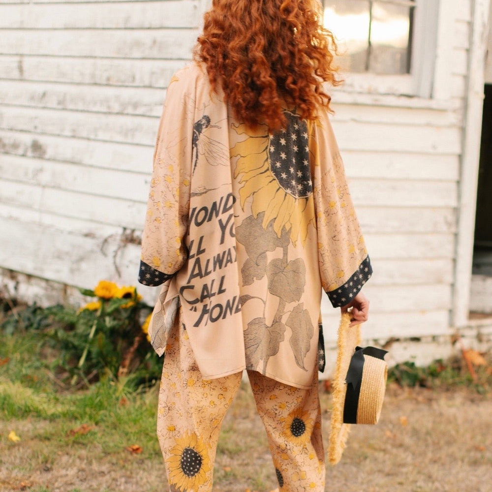 
                  
                    Model wearing the Milk & Honey Artist Pants featuring playful 1904 Brooklyn poster art and antique woodcut star and floral details in vintage-inspired tones – Market of Stars.
                  
                