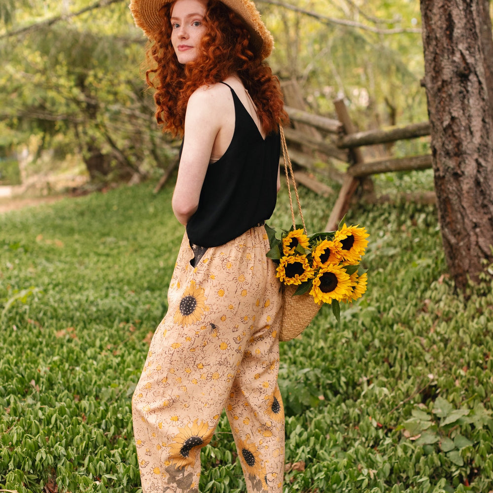 
                  
                    Model wearing the Milk & Honey Artist Pants featuring playful 1904 Brooklyn poster art and antique woodcut star and floral details in vintage-inspired tones – Market of Stars.
                  
                