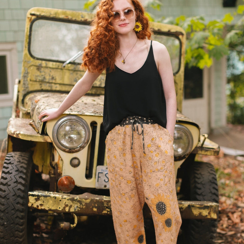 
                  
                    Model wearing the Milk & Honey Artist Pants featuring playful 1904 Brooklyn poster art and antique woodcut star and floral details in vintage-inspired tones – Market of Stars.
                  
                