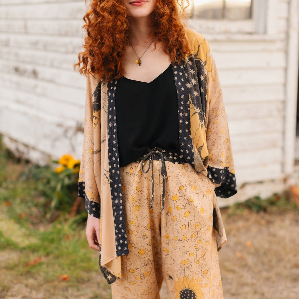 
                  
                    Model wearing the Milk & Honey Artist Pants featuring playful 1904 Brooklyn poster art and antique woodcut star and floral details in vintage-inspired tones – Market of Stars.
                  
                