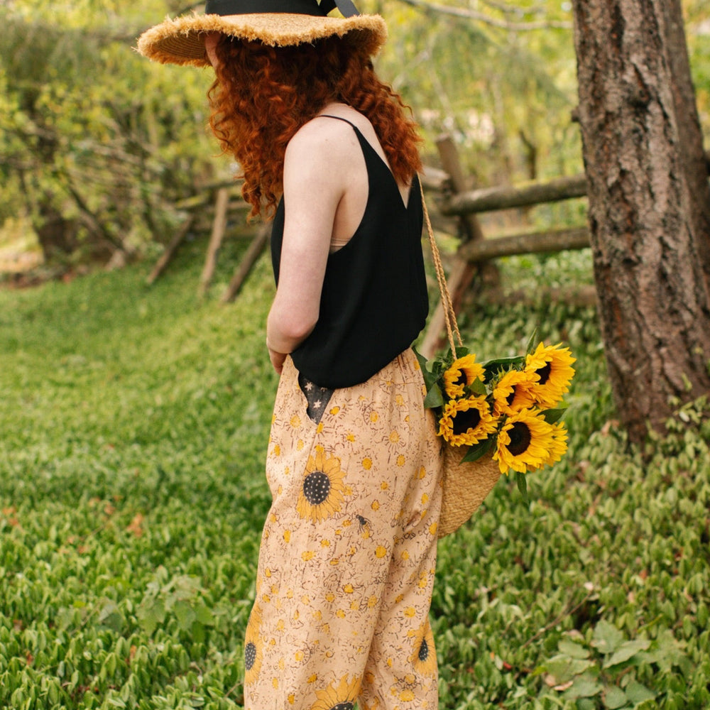
                  
                    Model wearing the Milk & Honey Artist Pants featuring playful 1904 Brooklyn poster art and antique woodcut star and floral details in vintage-inspired tones – Market of Stars.
                  
                