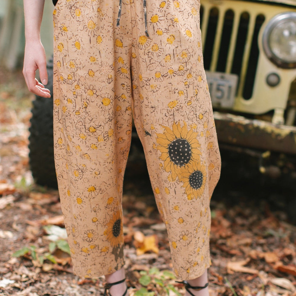 
                  
                    Model wearing the Milk & Honey Artist Pants featuring playful 1904 Brooklyn poster art and antique woodcut star and floral details in vintage-inspired tones – Market of Stars.
                  
                