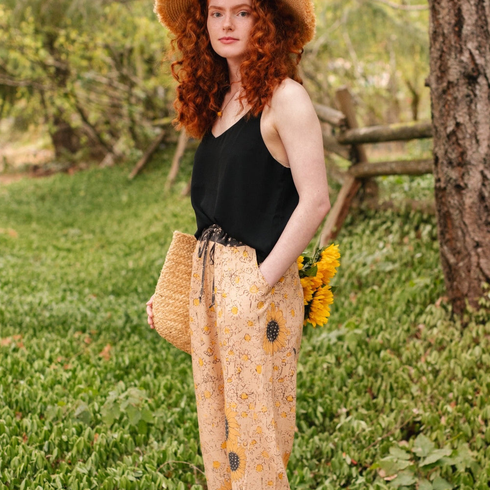 
                  
                    Model wearing the Milk & Honey Artist Pants featuring playful 1904 Brooklyn poster art and antique woodcut star and floral details in vintage-inspired tones – Market of Stars.
                  
                