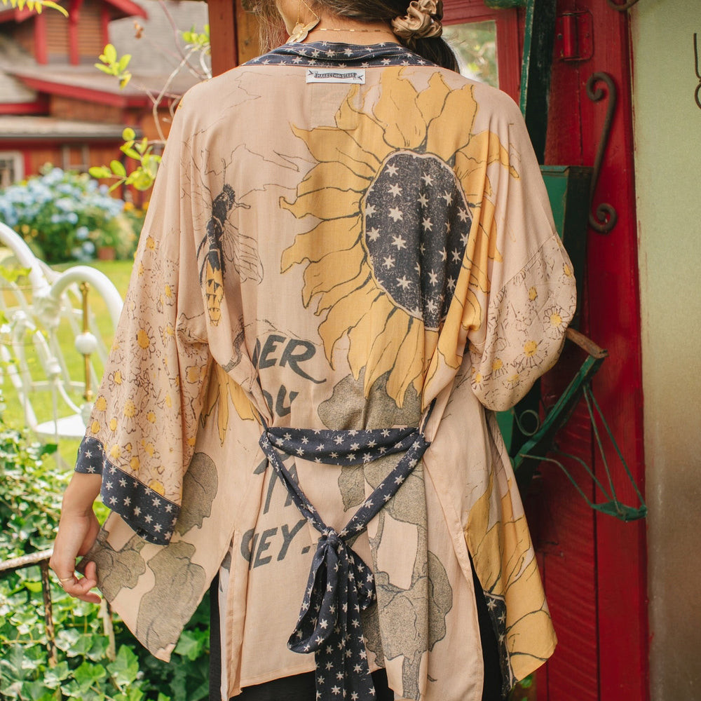 
                  
                    Model wearing our matinee length kimono featuring vintage-inspired Milk & Honey print with 1904 typography and floral woodcuts – Market of Stars
                  
                