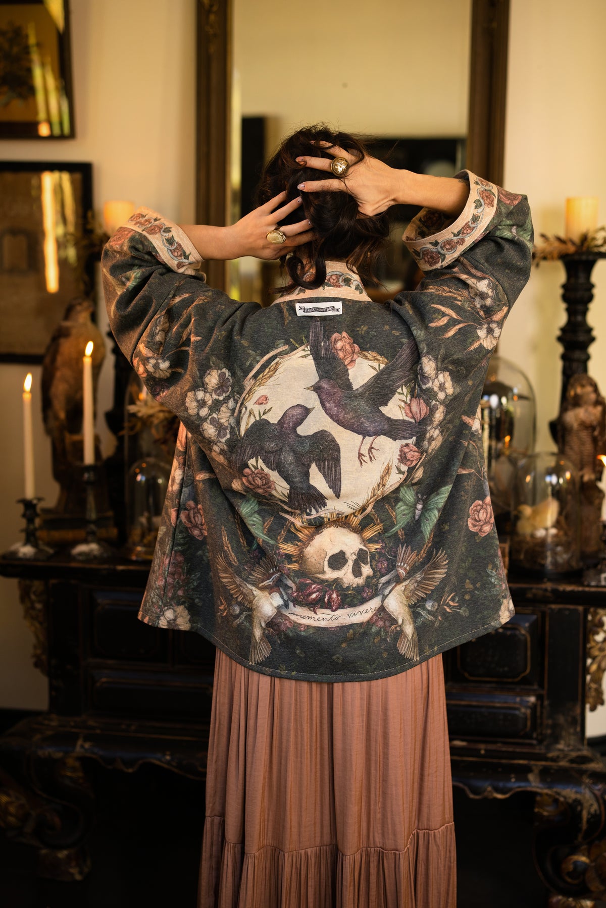 Model wearing a cozy fleece lined cottage cardigan ft. artwork created by Jessica Roux including two starlings beneath a full moon with flowers, butterflies, moths and botanical artwork - Market of Stars
