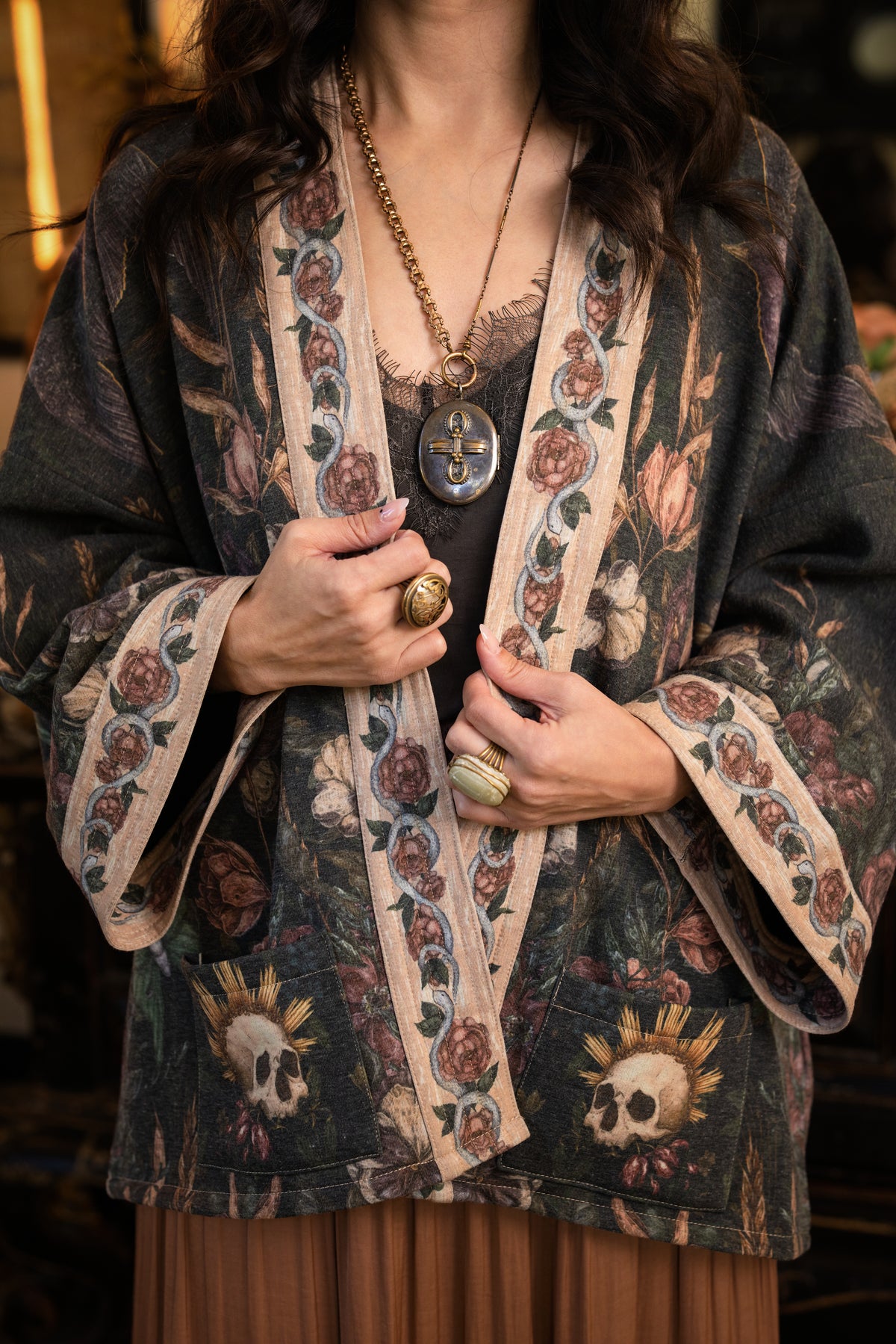 Model wearing a cozy fleece lined cottage cardigan ft. artwork created by Jessica Roux including two starlings beneath a full moon with flowers, butterflies, moths and botanical artwork - Market of Stars