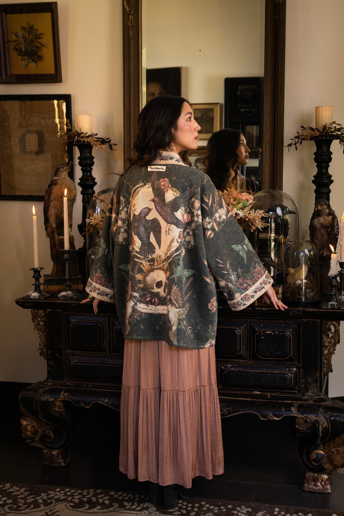 Model wearing a cozy fleece lined cottage cardigan ft. artwork created by Jessica Roux including two starlings beneath a full moon with flowers, butterflies, moths and botanical artwork - Market of Stars