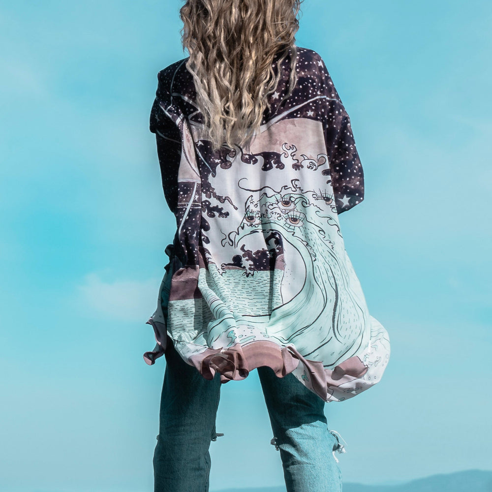 
                  
                    Model wearing Moonstruck Goddess Duster featuring original artwork by Leslie Love, inspired by the ocean, the night sky, and the artist’s handmade botanical inks – Market of Stars.
                  
                