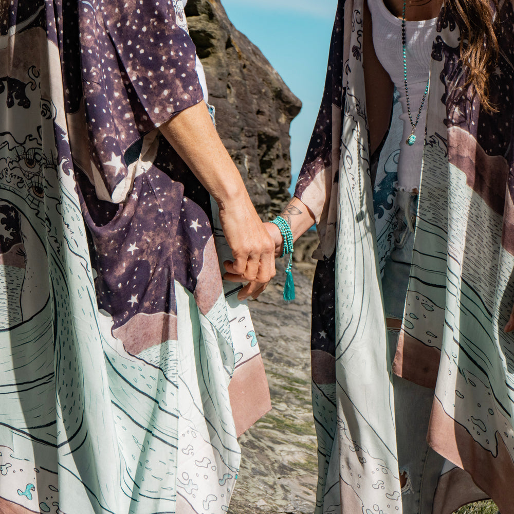 
                  
                    Model wearing Moonstruck Goddess Duster featuring original artwork by Leslie Love, inspired by the ocean, the night sky, and the artist’s handmade botanical inks – Market of Stars.
                  
                