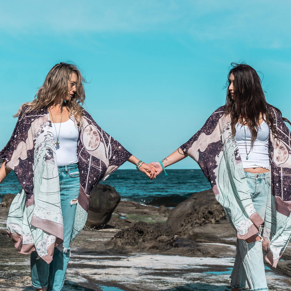 
                  
                    Model wearing Moonstruck Goddess Duster featuring original artwork by Leslie Love, inspired by the ocean, the night sky, and the artist’s handmade botanical inks – Market of Stars.
                  
                