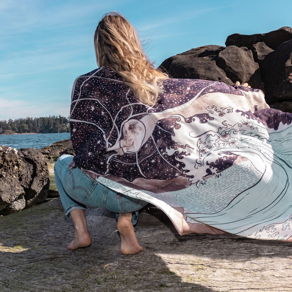 
                  
                    Model wearing Moonstruck Goddess Duster featuring original artwork by Leslie Love, inspired by the ocean, the night sky, and the artist’s handmade botanical inks – Market of Stars.
                  
                