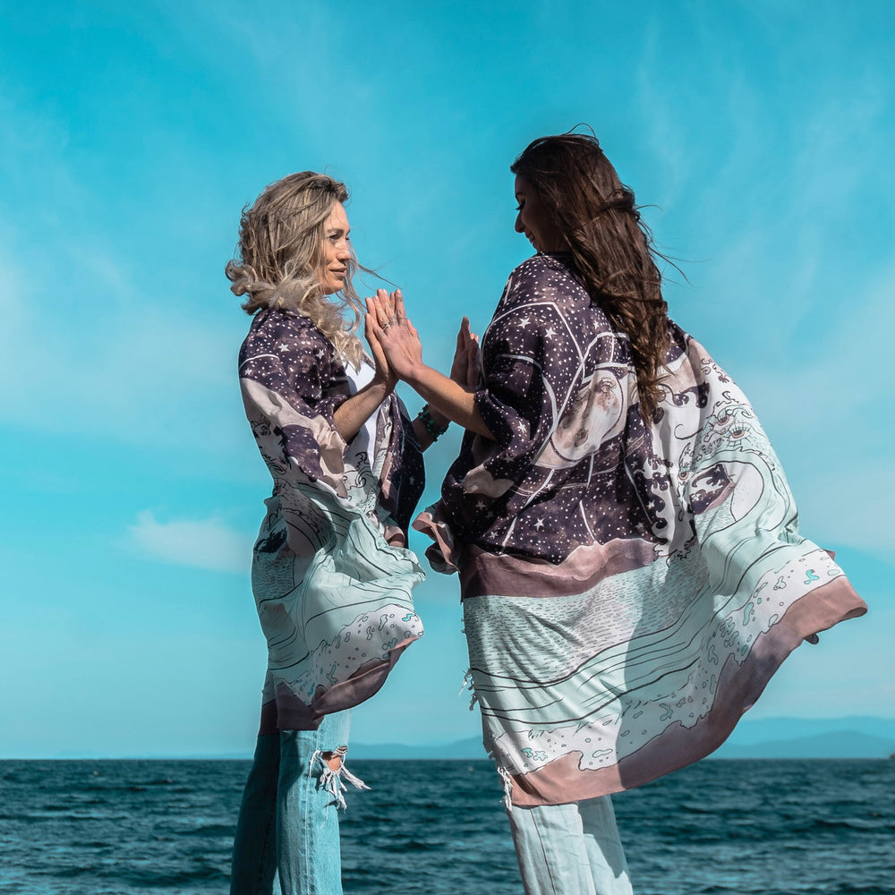 
                  
                    Model wearing Moonstruck Goddess Duster featuring original artwork by Leslie Love, inspired by the ocean, the night sky, and the artist’s handmade botanical inks – Market of Stars.
                  
                