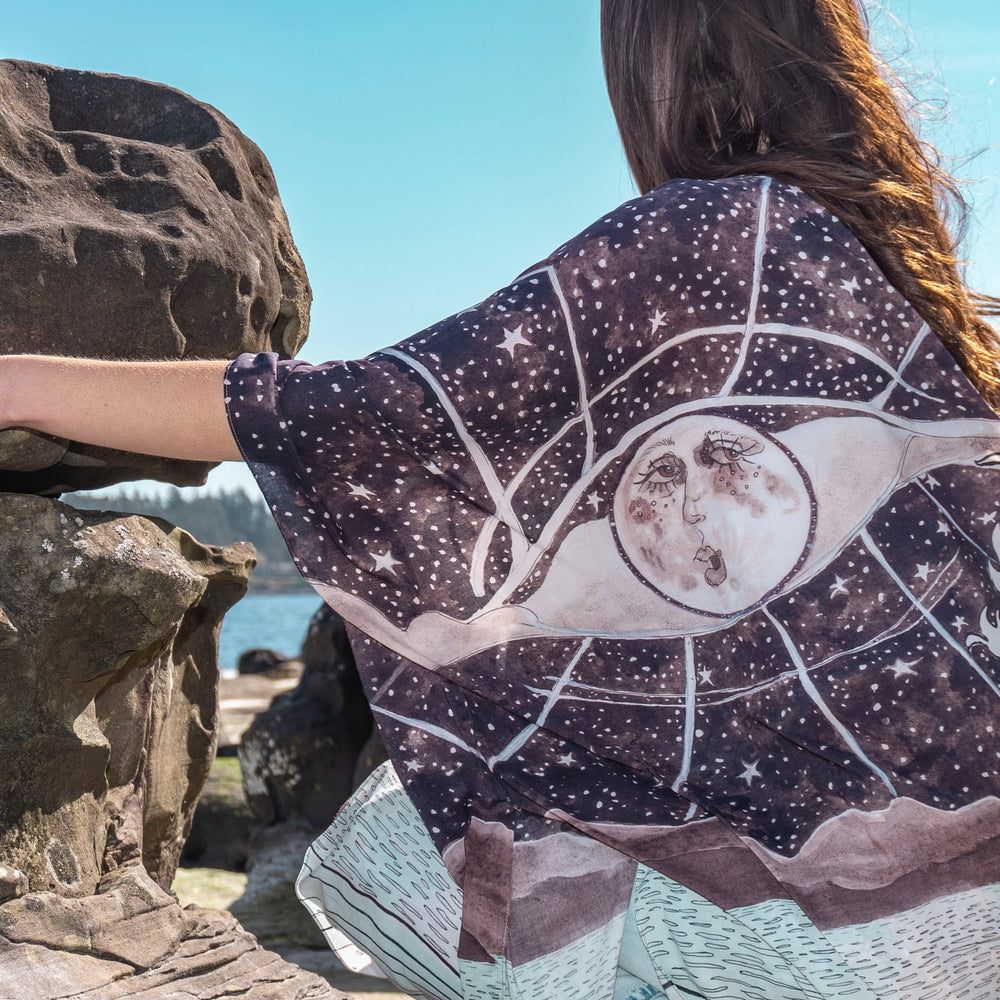 
                  
                    Model wearing Moonstruck Goddess Duster featuring original artwork by Leslie Love, inspired by the ocean, the night sky, and the artist’s handmade botanical inks – Market of Stars.
                  
                