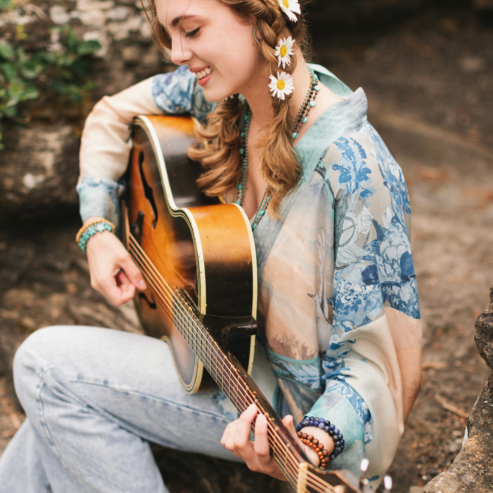 
                  
                    Model wearing our Peace Out Pixie Duster featuring 1800's perfumeur sign with gentle tones of blue & aqua, landscapes, clouds, dove and peace symbols -Market of Stars.
                  
                