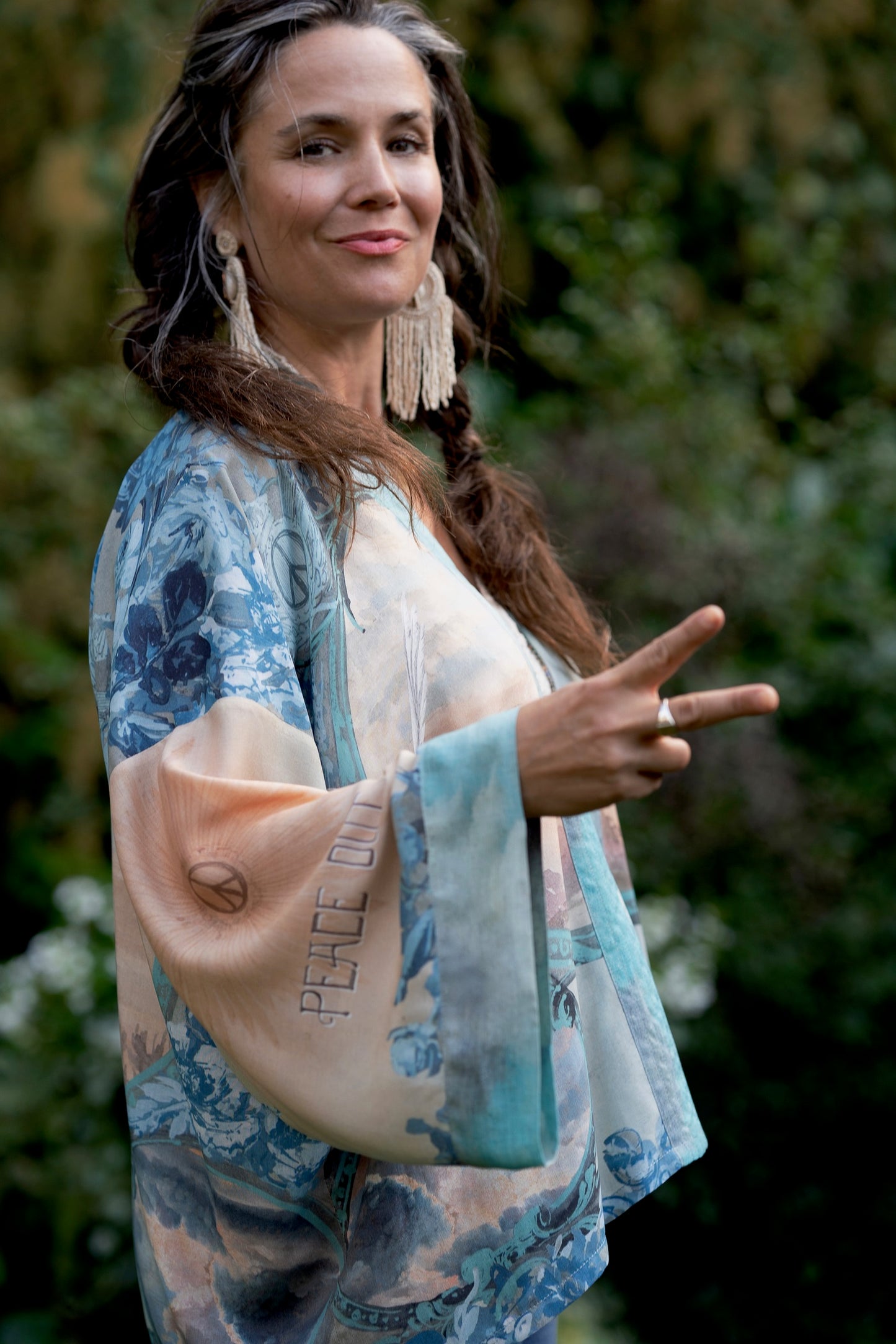 Model wearing our Peace Out Pixie Duster featuring 1800's perfumeur sign with gentle tones of blue & aqua, landscapes, clouds, dove and peace symbols -Market of Stars.