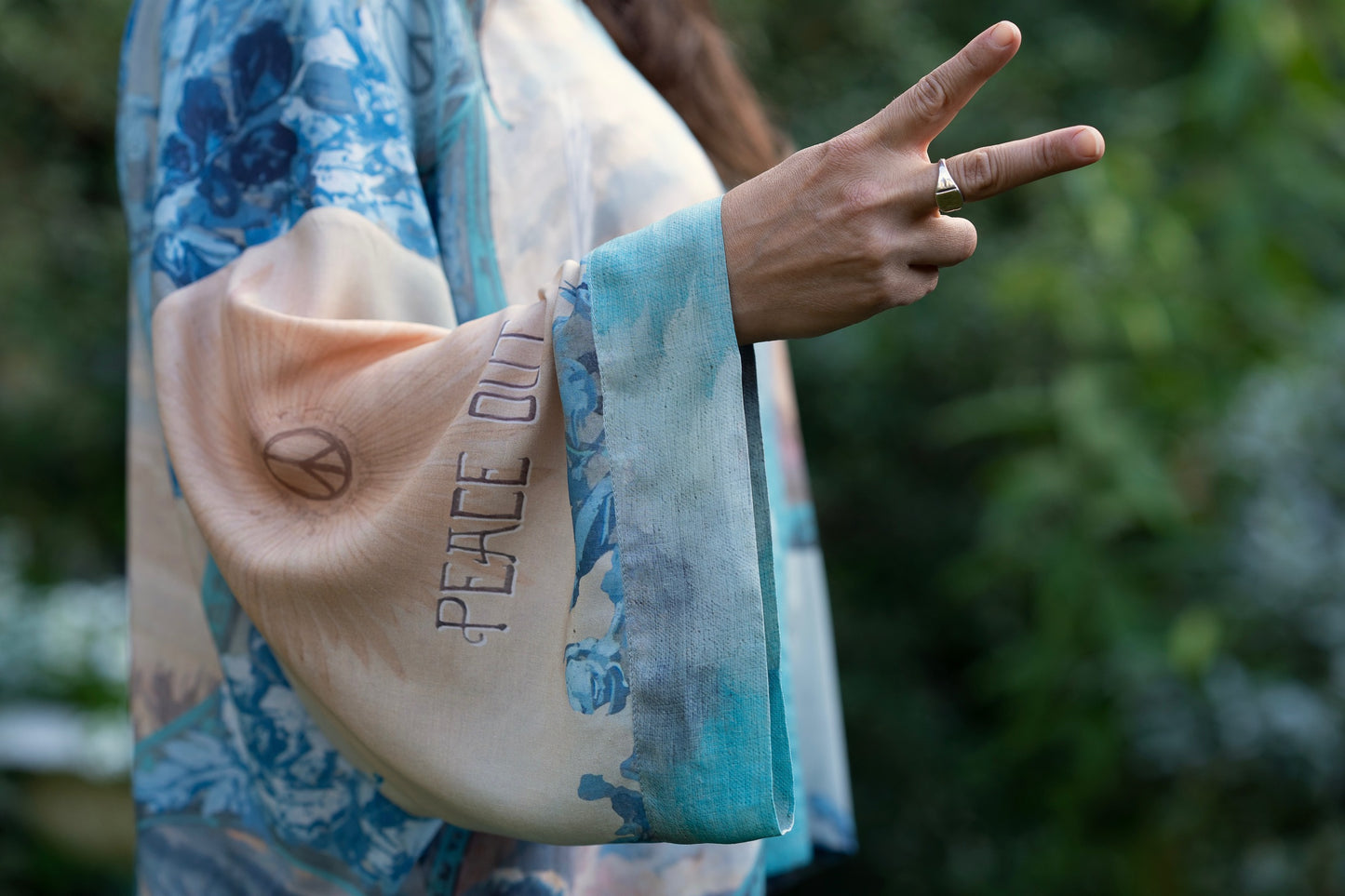 Model wearing our Peace Out Pixie Duster featuring 1800's perfumeur sign with gentle tones of blue & aqua, landscapes, clouds, dove and peace symbols -Market of Stars.