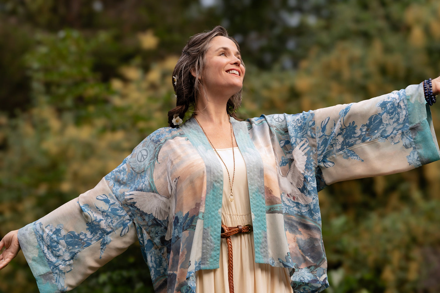 Model wearing our Peace Out Pixie Duster featuring 1800's perfumeur sign with gentle tones of blue & aqua, landscapes, clouds, dove and peace symbols -Market of Stars.
