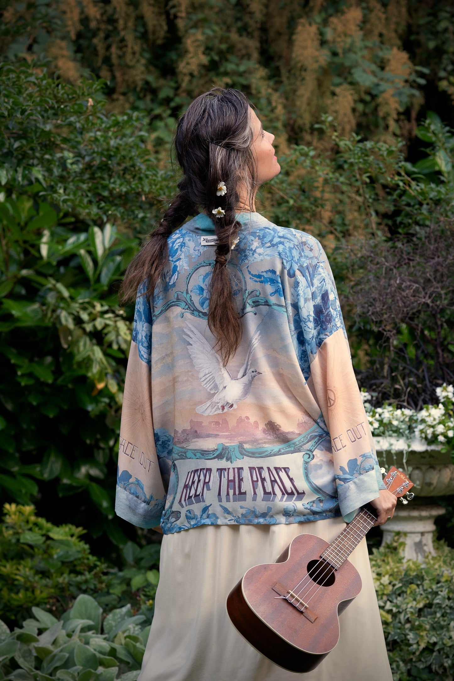 Model wearing our Peace Out Pixie Duster featuring 1800's perfumeur sign with gentle tones of blue & aqua, landscapes, clouds, dove and peace symbols -Market of Stars.