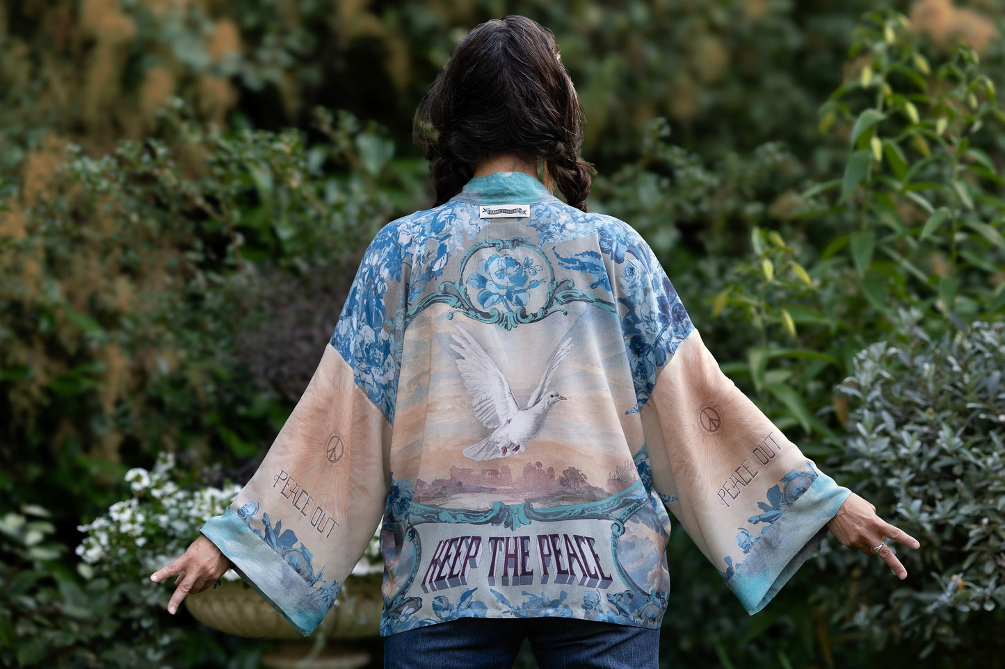 Model wearing our Peace Out Pixie Duster featuring 1800's perfumeur sign with gentle tones of blue & aqua, landscapes, clouds, dove and peace symbols -Market of Stars.