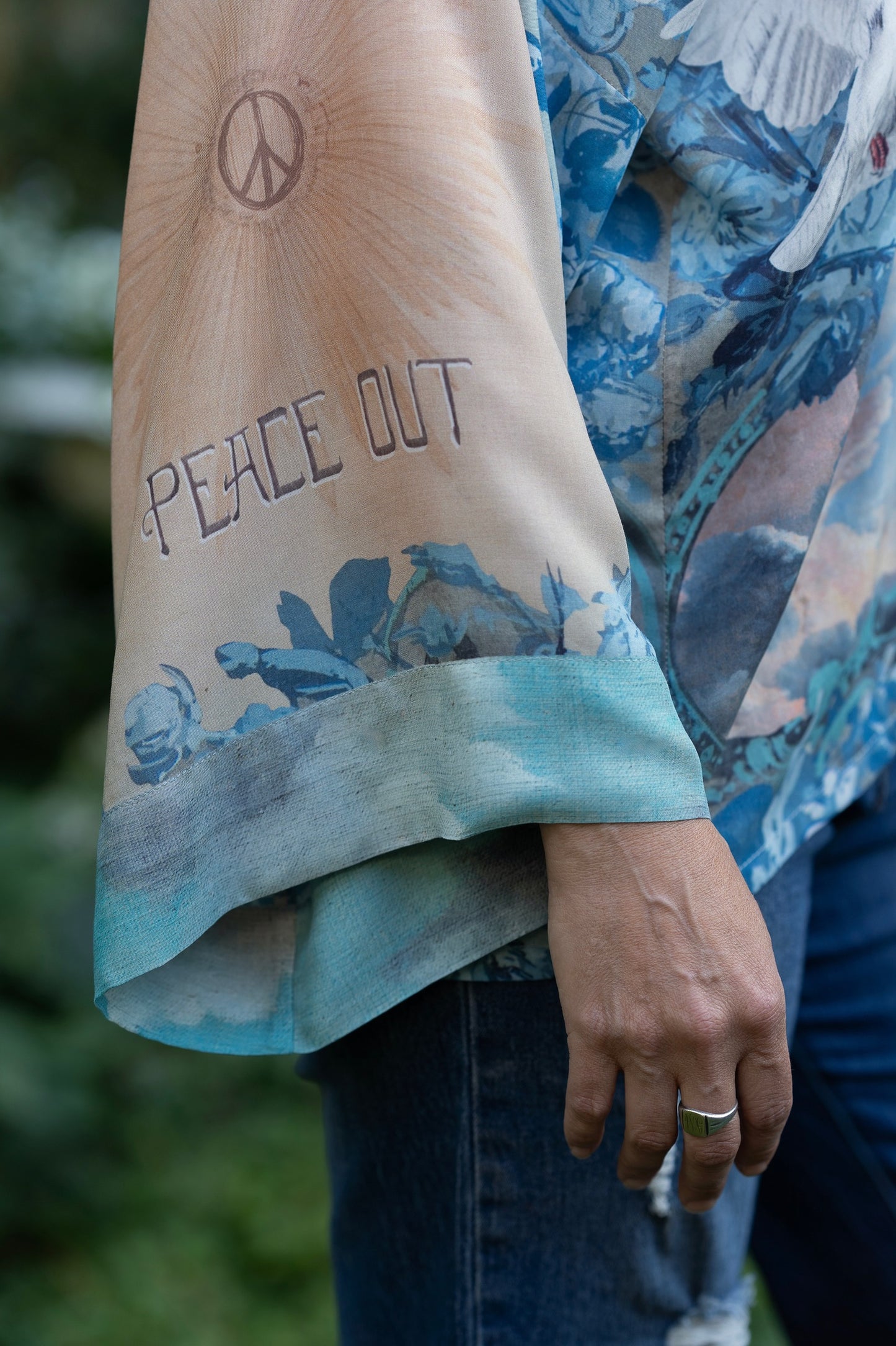 Model wearing our Peace Out Pixie Duster featuring 1800's perfumeur sign with gentle tones of blue & aqua, landscapes, clouds, dove and peace symbols -Market of Stars.