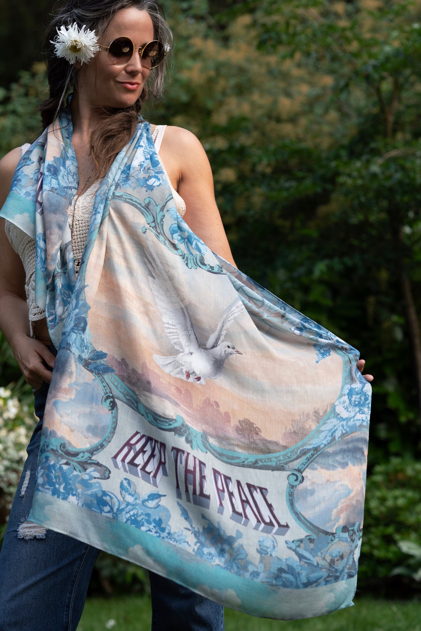 Model wearing our Peace Out scarf featuring 1800's perfumeur sign with gentle tones of blue & aqua, landscapes, clouds, dove, and peace symbols -Market of Stars