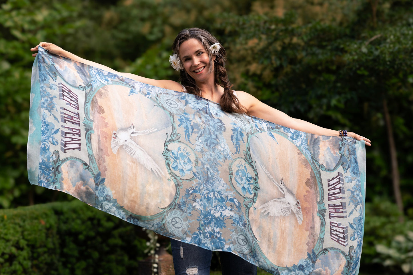 Model wearing our Peace Out scarf featuring 1800's perfumeur sign with gentle tones of blue & aqua, landscapes, clouds, dove, and peace symbols -Market of Stars