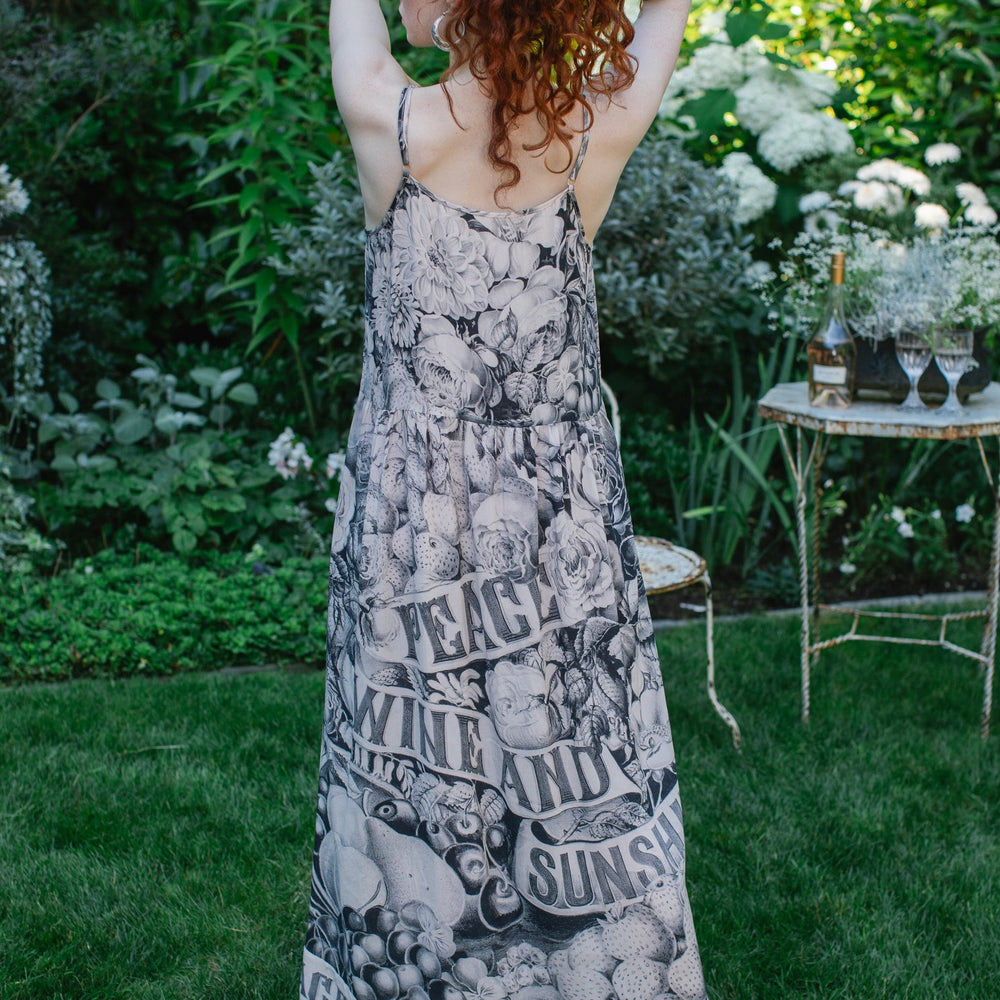 
                  
                    Model wearing Peace, Wine & Sunshine Bohéme Slip Dress featuring botanical collages and playful peace, wine and sunshine lettering on the hem – Market of Stars.
                  
                