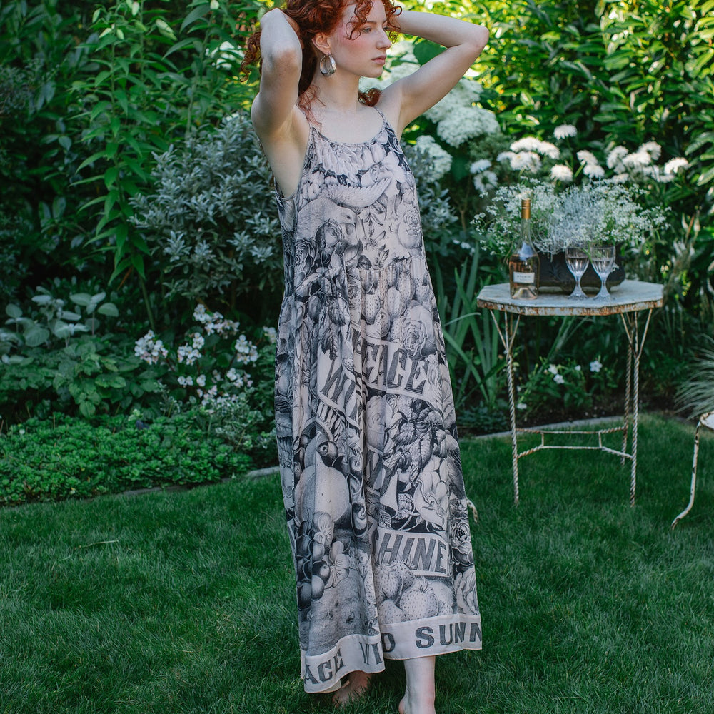 
                  
                    Model wearing Peace, Wine & Sunshine Bohéme Slip Dress featuring botanical collages and playful peace, wine and sunshine lettering on the hem – Market of Stars.
                  
                