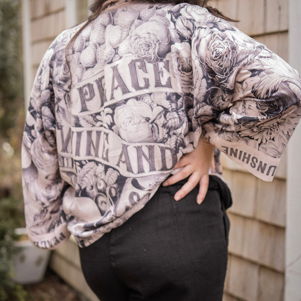 
                  
                    Model wearing Peace, Wine & Sunshine Bohéme Slip Dress featuring botanical collages and playful peace, wine and sunshine lettering on the hem – Market of Stars.
                  
                