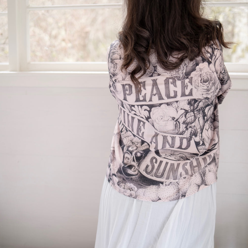 
                  
                    Model wearing Peace, Wine & Sunshine Bohéme Slip Dress featuring botanical collages and playful peace, wine and sunshine lettering on the hem – Market of Stars.
                  
                