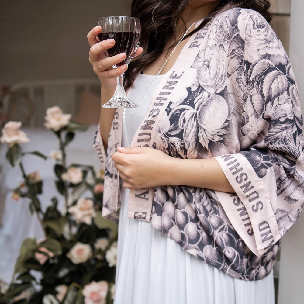 
                  
                    Model wearing Peace, Wine & Sunshine Bohéme Slip Dress featuring botanical collages and playful peace, wine and sunshine lettering on the hem – Market of Stars.
                  
                