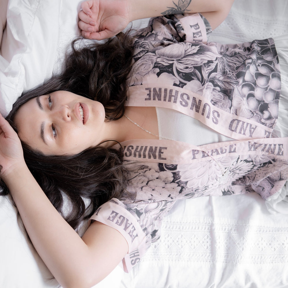 
                  
                    Model wearing Peace, Wine & Sunshine Bohéme Slip Dress featuring botanical collages and playful peace, wine and sunshine lettering on the hem – Market of Stars.
                  
                