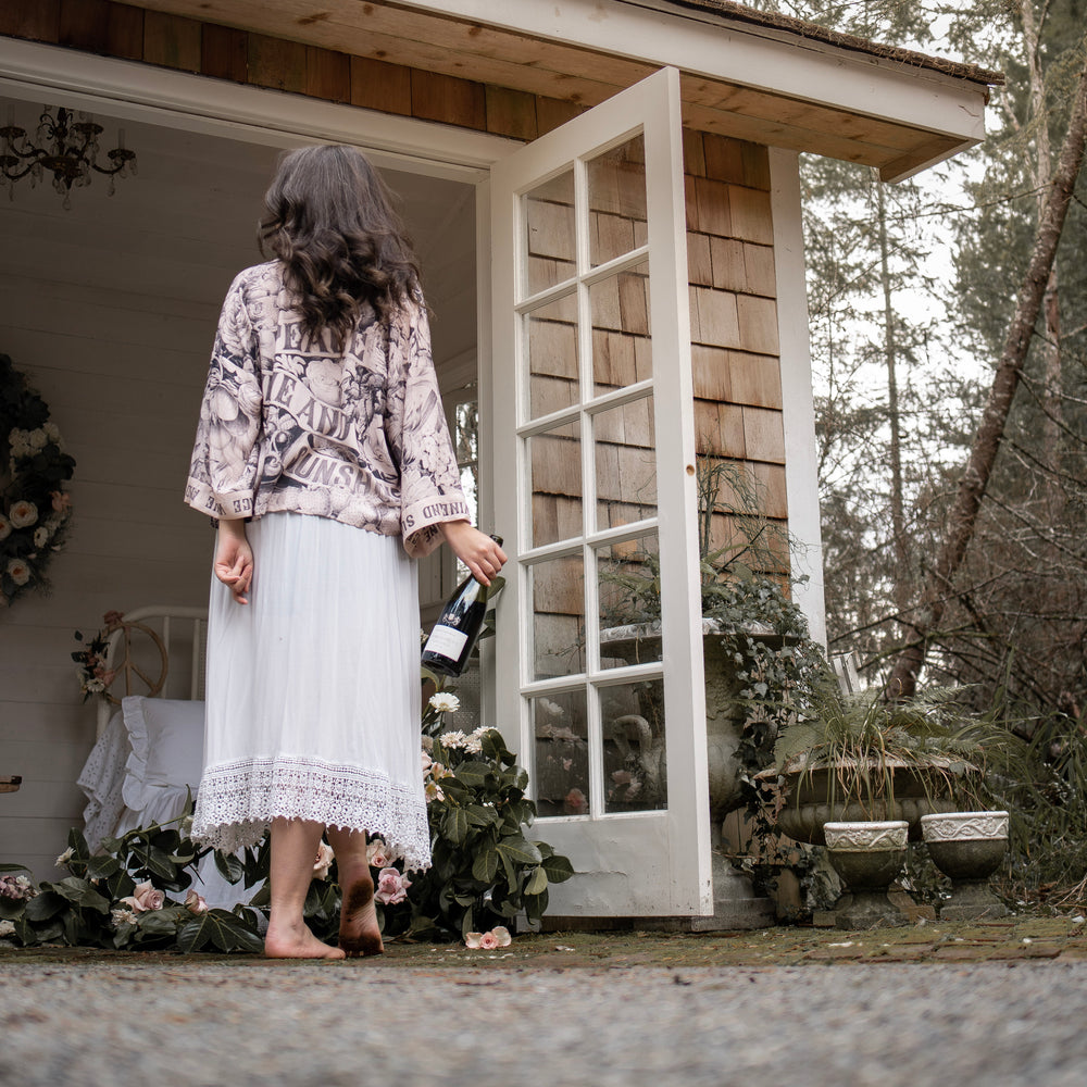 
                  
                    Model wearing Peace, Wine & Sunshine Bohéme Slip Dress featuring botanical collages and playful peace, wine and sunshine lettering on the hem – Market of Stars.
                  
                