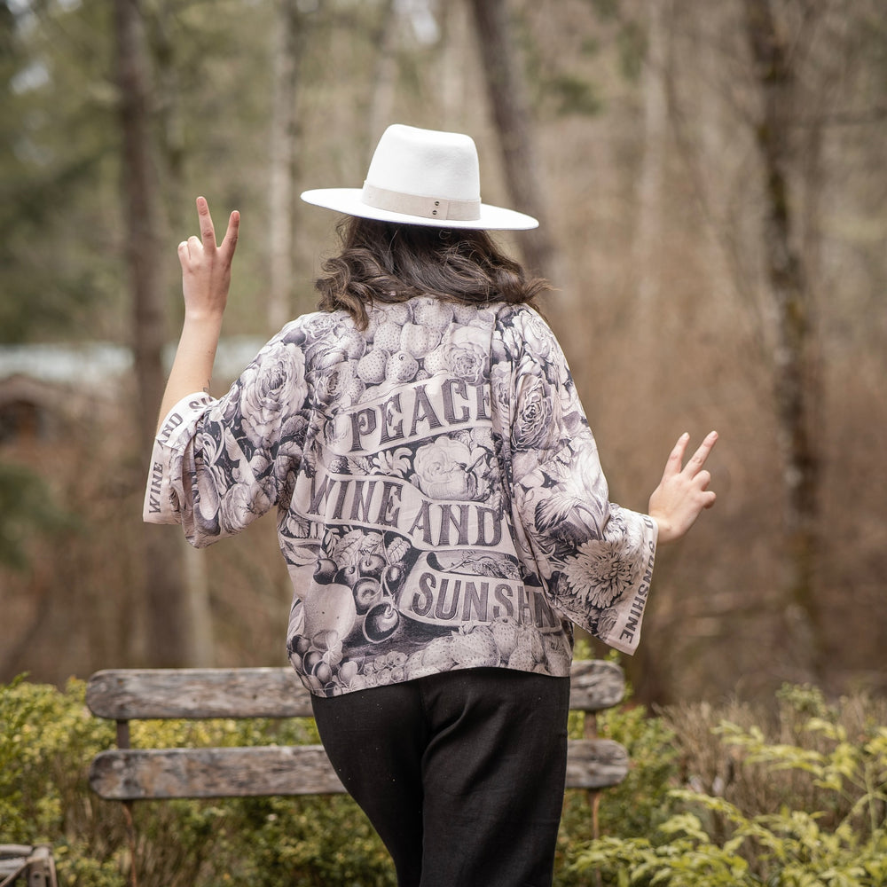 
                  
                    Model wearing Peace, Wine & Sunshine Bohéme Slip Dress featuring botanical collages and playful peace, wine and sunshine lettering on the hem – Market of Stars.
                  
                