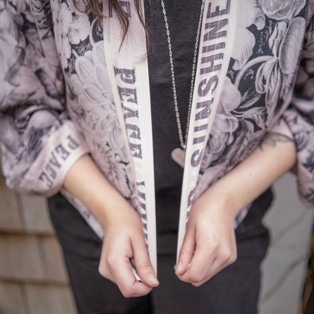 
                  
                    Model wearing Peace, Wine & Sunshine Bohéme Slip Dress featuring botanical collages and playful peace, wine and sunshine lettering on the hem – Market of Stars.
                  
                