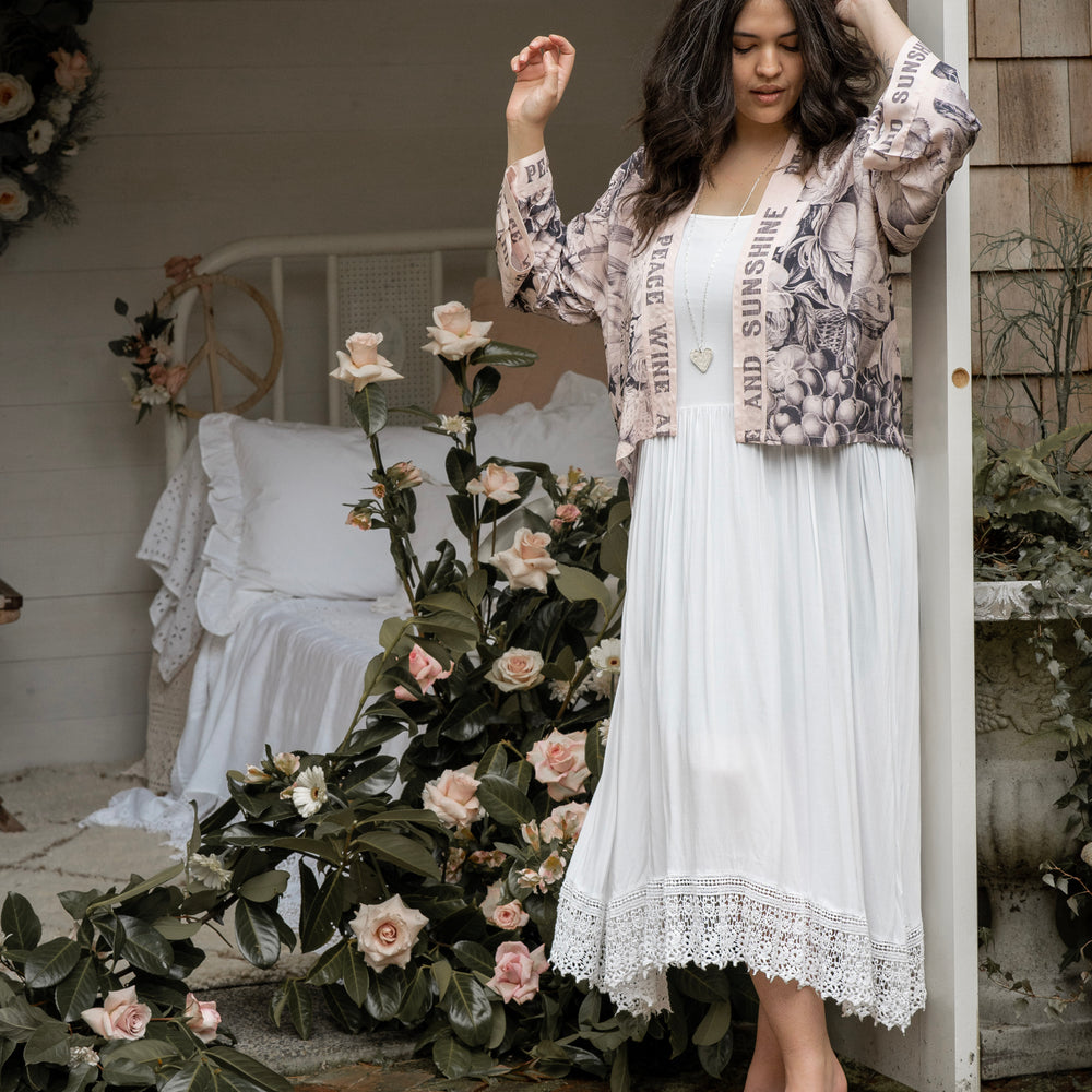 
                  
                    Model wearing Peace, Wine & Sunshine Bohéme Slip Dress featuring botanical collages and playful peace, wine and sunshine lettering on the hem – Market of Stars.
                  
                