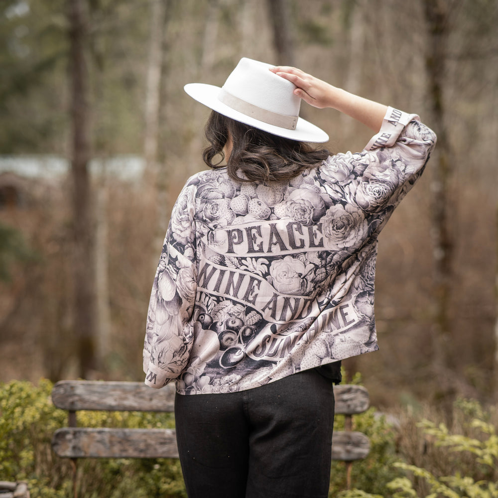 
                  
                    Model wearing Peace, Wine & Sunshine Bohéme Slip Dress featuring botanical collages and playful peace, wine and sunshine lettering on the hem – Market of Stars.
                  
                
