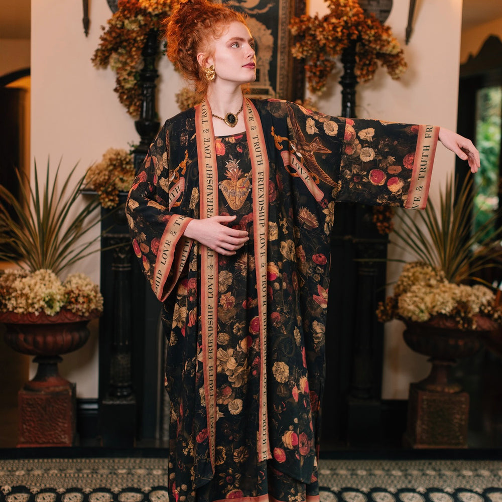 
                  
                    Model wearing a full-length bamboo-viscose duster featuring a collage of antique artwork with romance, loyalty, and old-world beauty - Market of Stars
                  
                