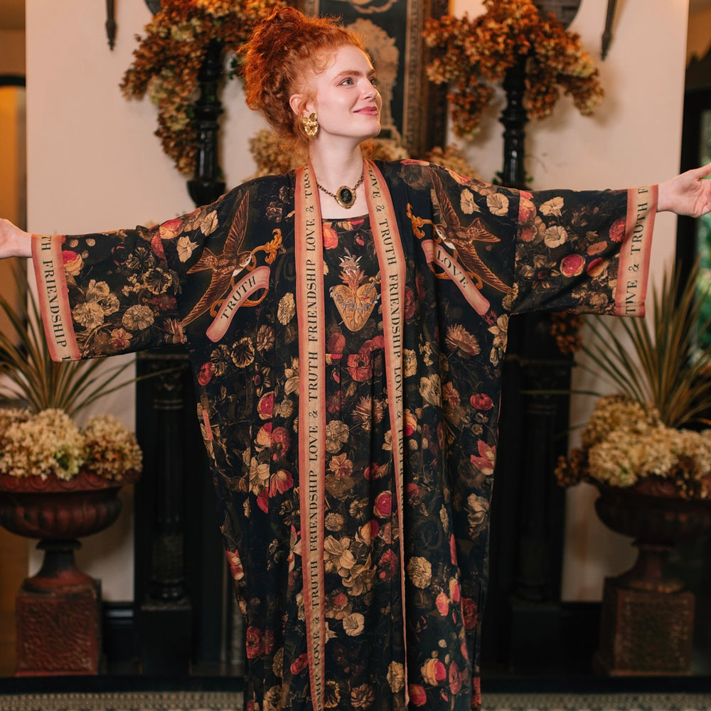 
                  
                    Model wearing a full-length bamboo-viscose duster featuring a collage of antique artwork with romance, loyalty, and old-world beauty - Market of Stars
                  
                
