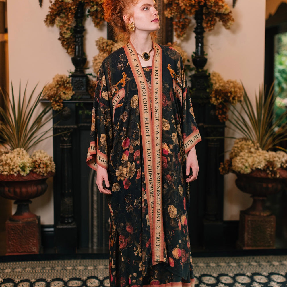 
                  
                    Model wearing a full-length bamboo-viscose duster featuring a collage of antique artwork with romance, loyalty, and old-world beauty - Market of Stars
                  
                