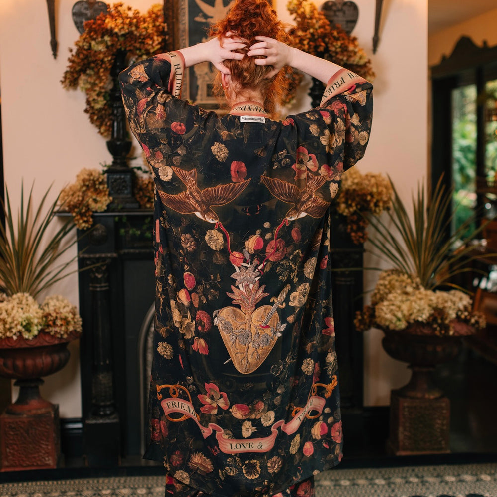 
                  
                    Model wearing a full-length bamboo-viscose duster featuring a collage of antique artwork with romance, loyalty, and old-world beauty - Market of Stars
                  
                